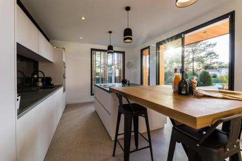 une cuisine avec une table en bois et une grande fenêtre dans l'établissement SPRING KEYWEEK - Contemporary villa with pool in the hea, à Anglet