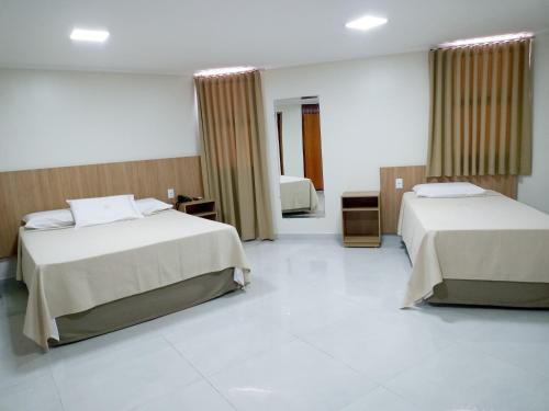 a hotel room with two beds and a bathroom at Tawfiq´s Palace Hotel in Barra do Garças