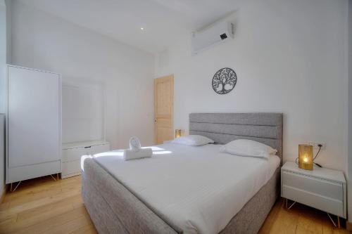 - une chambre avec un grand lit blanc et une horloge murale dans l'établissement IMMOGROOM - T3 - Garden - Quiet - Air conditioning, à Cannes