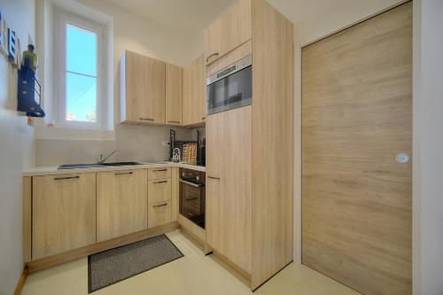 Elle comprend une petite cuisine avec des placards en bois et une fenêtre. dans l'établissement IMMOGROOM - T3 - Garden - Quiet - Air conditioning, à Cannes