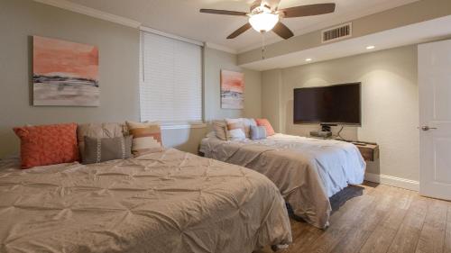 a bedroom with two beds and a flat screen tv at Dolphin Point 402B - 2BR on Holiday Isle in Destin