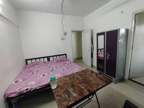 a bedroom with a purple bed and a wooden table at GharApna Hostel in Mumbai
