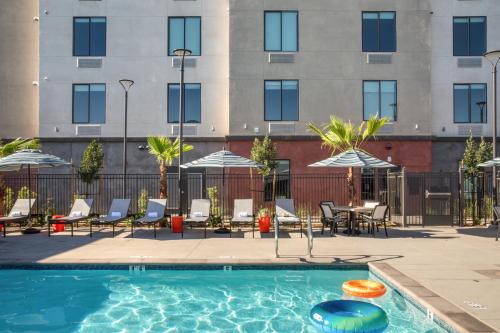 a swimming pool with chairs and tables and a building at Ayres Hotel Rialto Fontana in Rialto