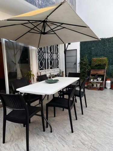 Biały stół z krzesłami i parasolem w obiekcie Mar y Tierra w mieście Manta