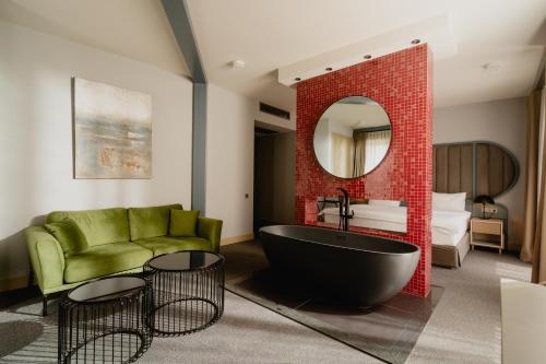 a bathroom with a black tub and a green couch at STROFI Boutique Hotel in Tbilisi City