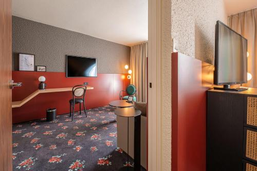 a hotel room with a flat screen tv and red walls at Best Western Porte du Forez in Andrézieux-Bouthéon