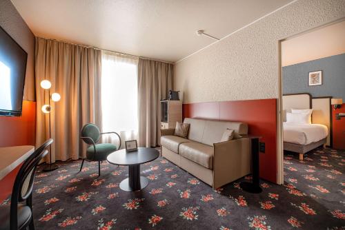 a hotel room with a couch and a bed and a mirror at Best Western Porte du Forez in Andrézieux-Bouthéon