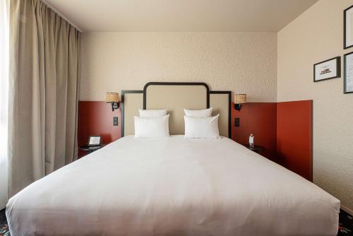 a large bed with two white pillows in a room at Best Western Porte du Forez in Andrézieux-Bouthéon