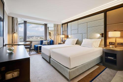 una camera d'albergo con un grande letto e una scrivania di Hilton Budapest a Budapest