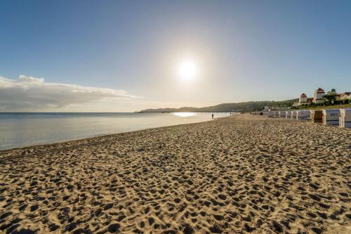 a sandy beach with the sun rising over the water at Dorint Strandhotel Binz/Rügen in Binz