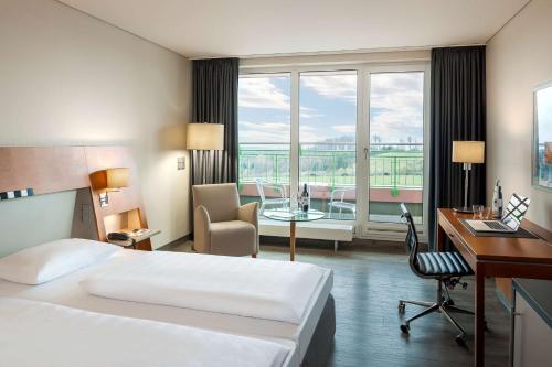 a hotel room with a bed and a desk and a table at Dorint Am Nürburgring Hocheifel in Nürburg