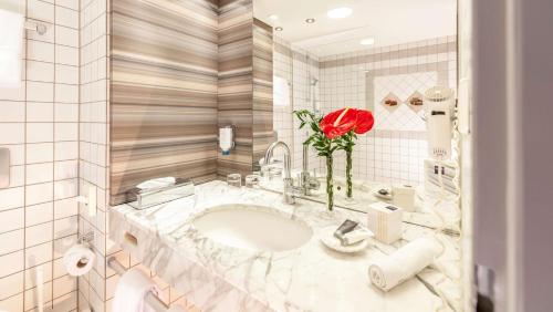 a bathroom with a sink and a red rose at Dorint Am Nürburgring Hocheifel in Nürburg