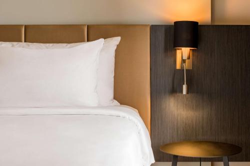 a bed with a white pillow and a stool next to it at Gurmon Hotels Sohna Road Gurugram, a member of Radisson Individuals in Sohna