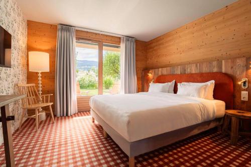 una camera con un grande letto e una grande finestra di Auberge de l'Orangerie - Sure Hotel Collection by Best Western a Sallanches