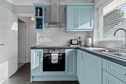 a kitchen with blue cabinets and a sink at Brynawelon - Wonderful Sea and Harbour Views in Saundersfoot