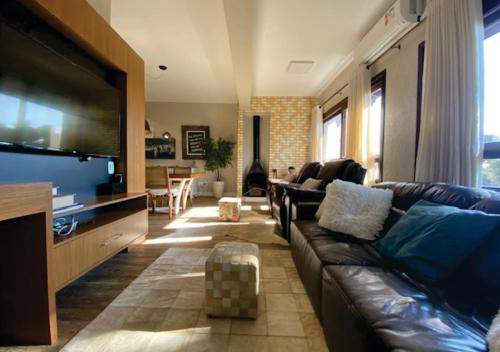 un soggiorno con divano e TV a schermo piatto di Duplex Accorsi Gramado, COM 2 SUITES a Gramado