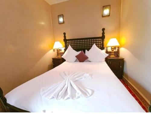 a bedroom with a large white bed with two lamps at RIAD GREEN LOTUS in Marrakech