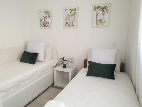 2 letti in una camera bianca con cuscini verdi di Cidade_Berço House a Guimarães