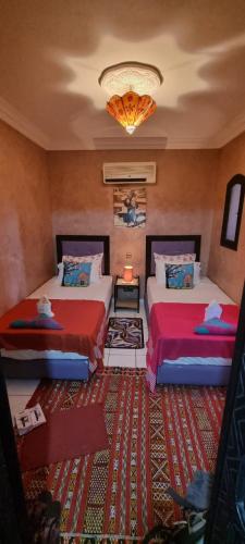 a bedroom with two beds and a chandelier at RIAD GREEN LOTUS in Marrakech