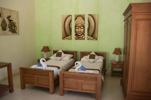 a room with two beds and a statue of a head at Guesthouse Rumah Senang in Kalibaru