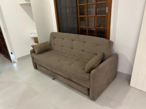 a brown couch sitting in a living room at Studios Aromas do Campeche - Floripa in Florianópolis