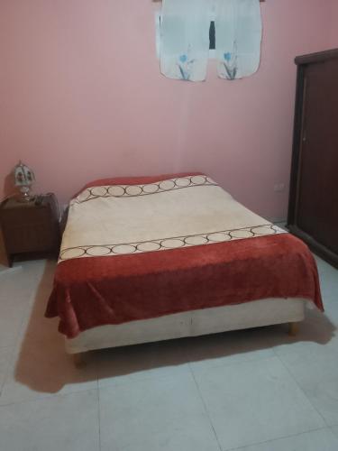 Una cama en una habitación con una manta roja. en Felipe Chalet en La Falda