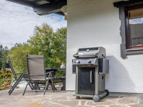 a grill and chairs on a patio with a table at Chalet Pölven in Bad Häring