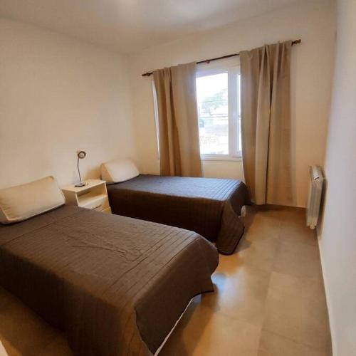 due letti in una piccola stanza con una finestra di El Descanso a Olavarría