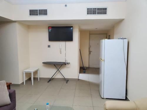 沙迦的住宿－bed space available in al majaaz 1 sharjah，客厅配有冰箱和桌子