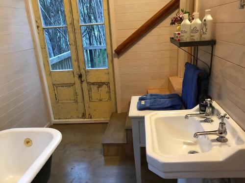 La salle de bains est pourvue d'un lavabo et d'une porte. dans l'établissement Kanuka Retreat, à Akaroa