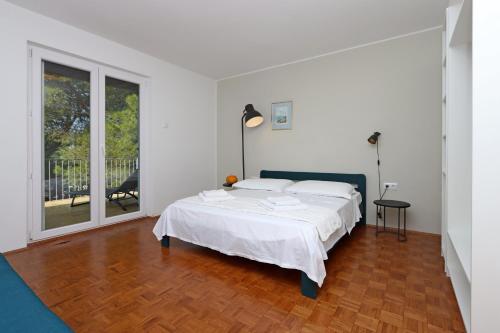 a white bedroom with a bed and a large window at Apartments by the sea Omisalj, Krk - 5298 in Omišalj