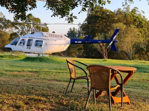 a table and two chairs and a helicopter in a field at Vacy Hunter Valley Lodge in Vacy