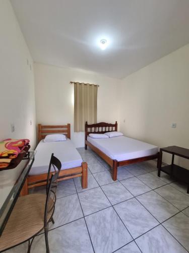 a room with two beds and a table and chairs at Pousada Renascer in Cuiabá
