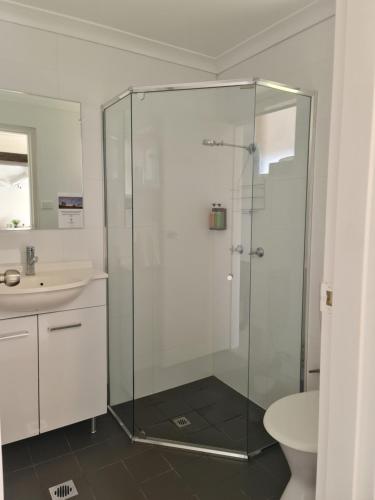 a bathroom with a glass shower and a sink at Vacy Hunter Valley Lodge in Vacy