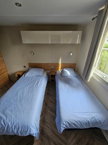2 bedden in een kamer met witte lakens en een raam bij marie & cyrille in Lattes