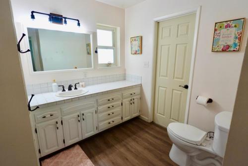 a bathroom with a sink and a toilet and a mirror at Modern Charm Meets Cozy Elegance in Fowler