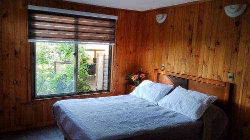 a bedroom with a bed with a large window at Cabaña Uka Moana in Hanga Roa