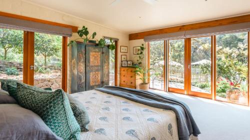 ein Schlafzimmer mit einem Bett und einigen Fenstern in der Unterkunft Scribbleswood in Red Hill