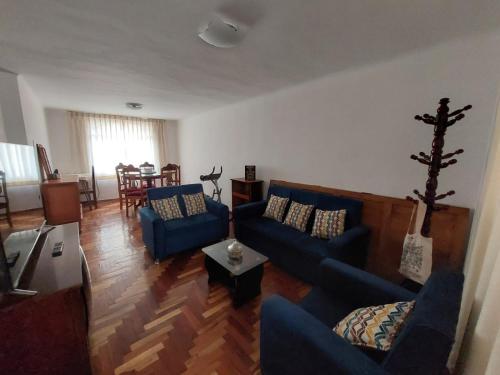 una sala de estar con 2 sofás azules y una mesa. en Piso Holbie Cusco, en Cusco