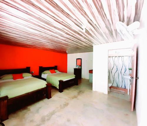ドラケにあるHostel Osa Tucan Corcovadoの赤い壁のベッドルーム1室(ベッド2台付)