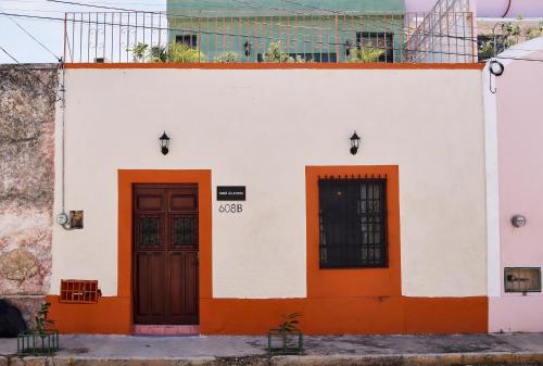 a white and orange building with two doors at Kuka y Letras in Mérida