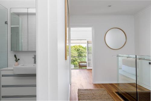 Baño blanco con espejo y lavabo en A Perfect Stay - 1 James Cook Apartments, en Byron Bay