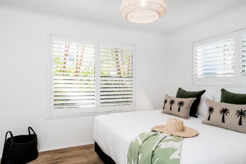 a white bedroom with a bed with a hat on it at A Perfect Stay - 3 Salty Sisters in Byron Bay