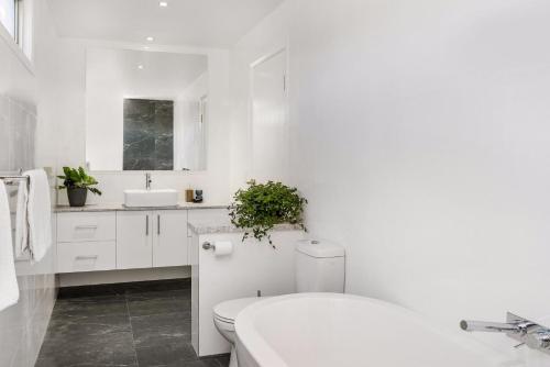 a white bathroom with a toilet and a sink at A Perfect Stay - Aditi in Byron Bay