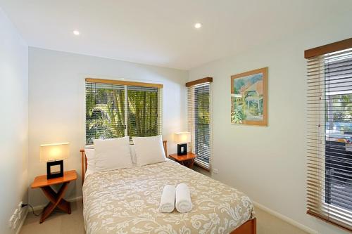 a bedroom with a bed with two lamps and two windows at A Perfect Stay - Abode at Byron in Ewingsdale