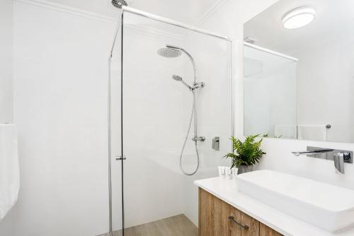 a white bathroom with a shower and a sink at A Perfect Stay - Amity at Seadrift in Byron Bay
