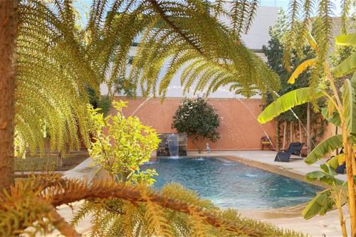 a swimming pool in a yard with palm trees at Riyad Anis - VacayX - MARRAKECH in Marrakesh