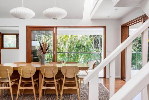 a dining room with a table and chairs and a large window at Beachcomber Blue - beachfront villa with pool in Byron Bay