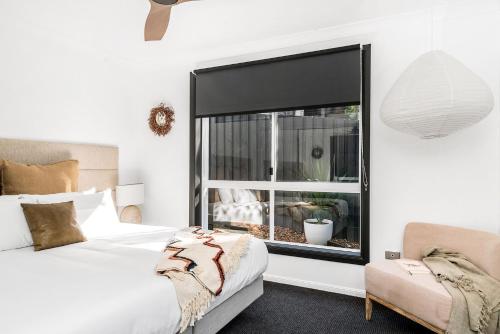 a bedroom with a bed and a window and a chair at A Perfect Stay - Black Star in Byron Bay