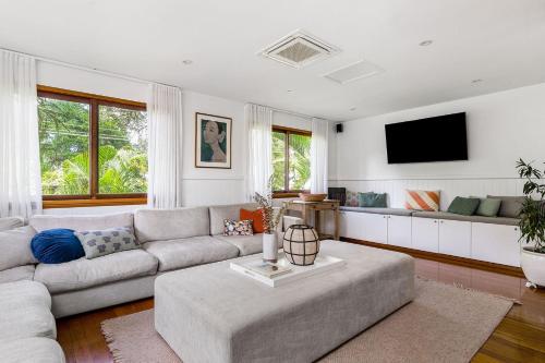 a living room with a couch and a tv at Byron Blisshouse - multi-home retreat with pool in Byron Bay